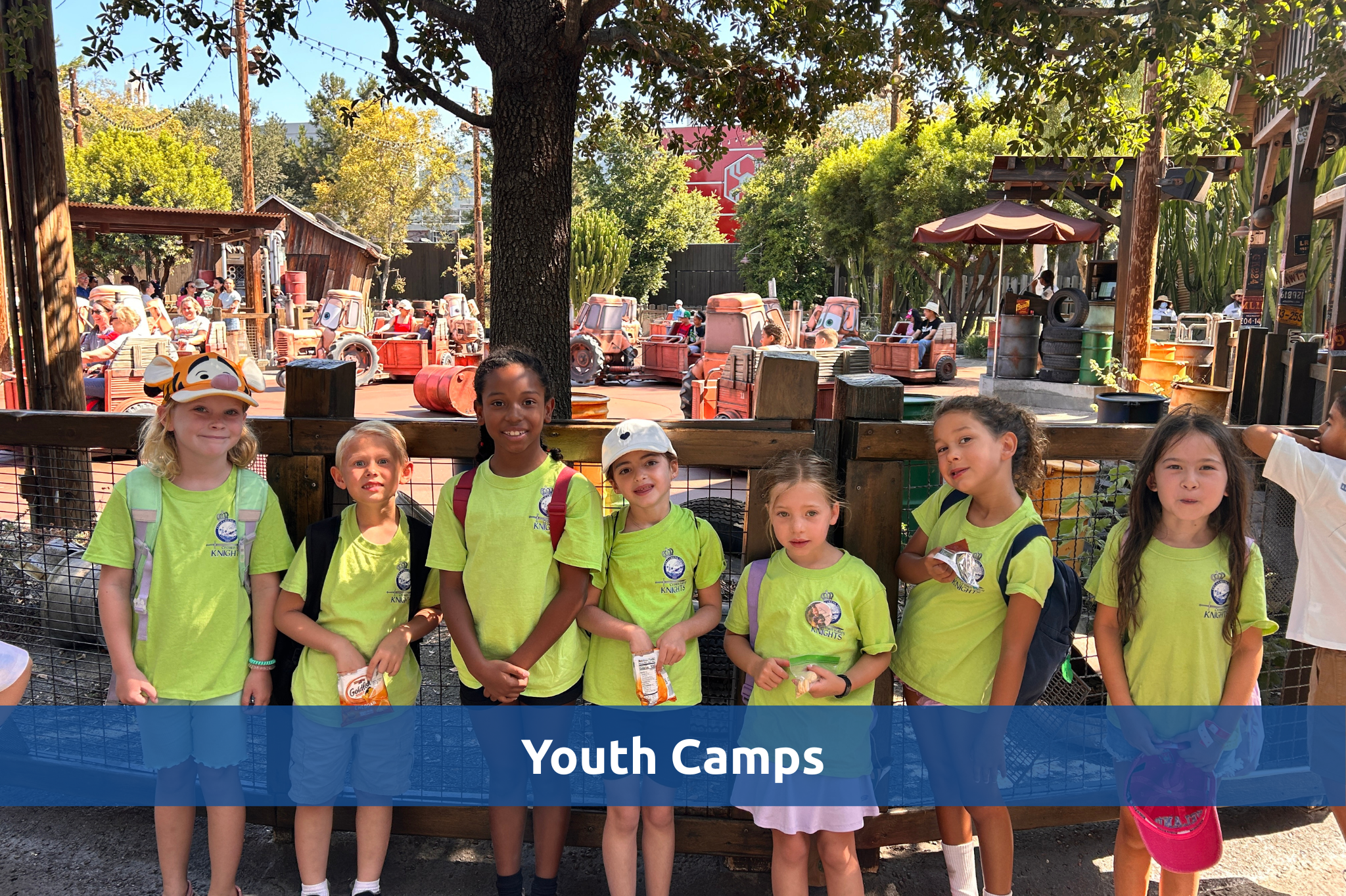 Group of children in matching shirts pose together during a camp outing at Disneyland